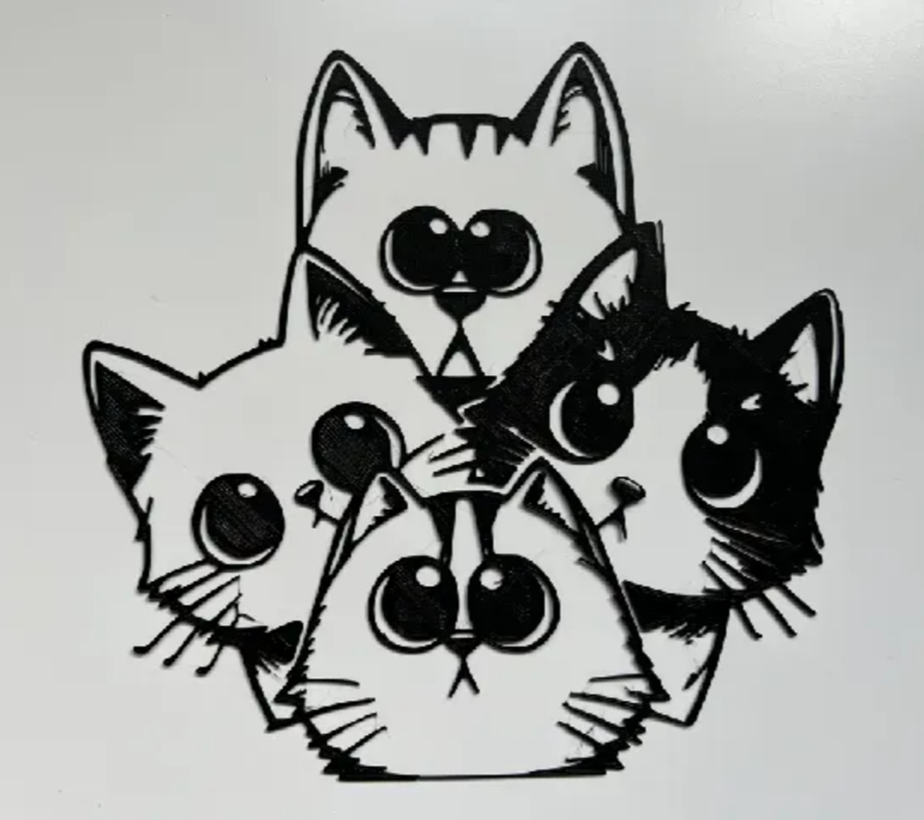 Arte de parede impressa em 3D com filamento PLA preto representando quatro gatinhos cartoon com olhos grandes