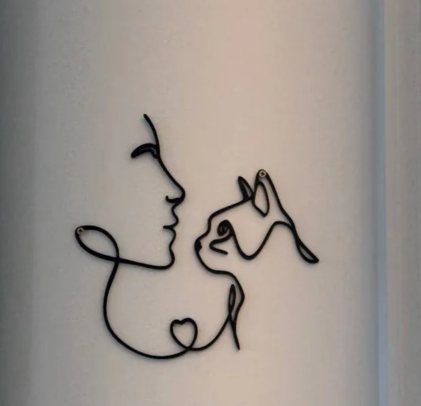 Arte de parede em arame preto com traço único representando tutora e gato frente a frente com coração