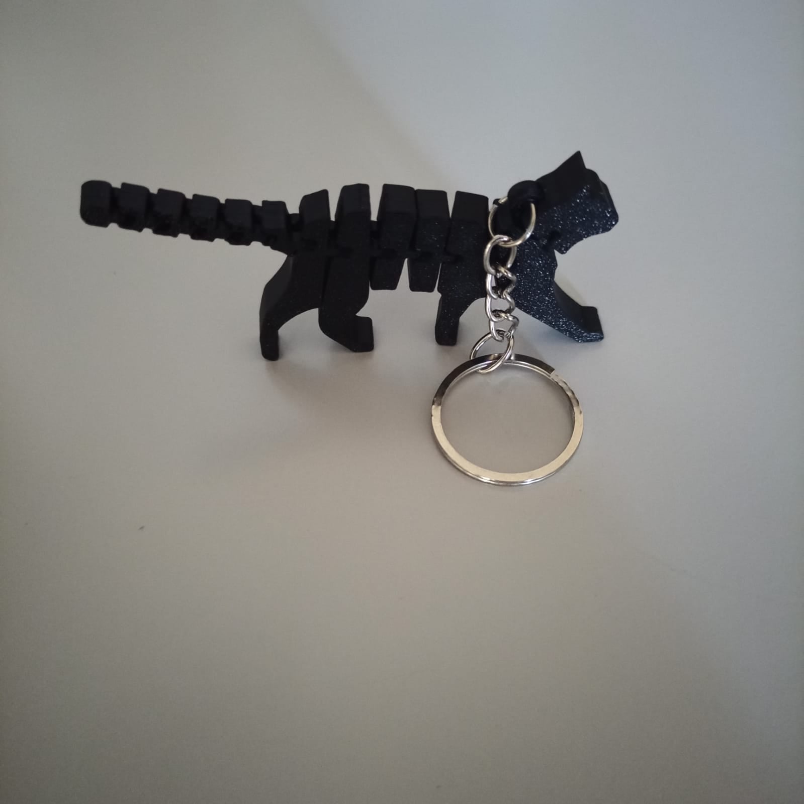 Chaveiro gato articulado impresso em 3D apoiado na mesa, mostrando volume e articulação do corpo